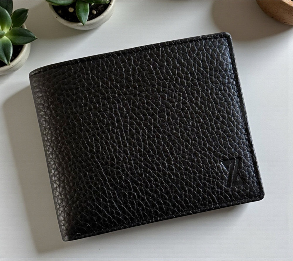 Black leather wallet on a light surface with plants in the background