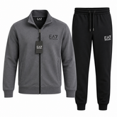 A two-piece men's loungewear set by EA7, featuring a heather gray zip-up jacket with a black zipper and a black hangtag, paired with black sweatpants with a white EA7 logo on the left thigh.