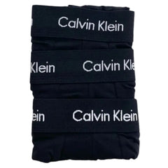 Three folded pairs of black Calvin Klein briefs stacked vertically, showing the white brand name printed on the elastic waistbands against a plain white background.