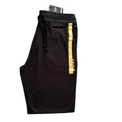 Black BOSS jogger pants with a vertical gold stripe and gold BOSS lettering on the side, shown on a white background with a hangtag.