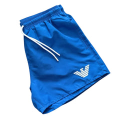 Blue athletic shorts with a white drawstring and a white embroidered eagle logo on the lower left leg, shown against a plain white background.