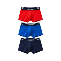 Three pairs of Lacoste men's boxer briefs stacked vertically on a white background, featuring red, royal blue, and navy blue fabrics with black waistbands and white brand lettering.