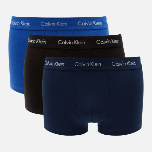Three pairs of Calvin Klein men's low-rise trunk underwear in blue, black, and blue patterns, with the Calvin Klein brand logo on the waistband.