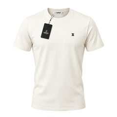 An off-white short-sleeve crewneck t-shirt with a small black embroidered logo on the left chest, featuring a black hangtag with gold lettering, displayed on a clean white background.