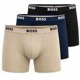 Three pairs of BOSS men's boxer briefs stacked diagonally on a white background, showing the beige, navy, and black colors with the BOSS logo on the waistbands.