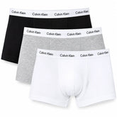 Three pairs of Calvin Klein men's boxer briefs in black, heather gray, and white, arranged in a diagonal stack on a plain white background.