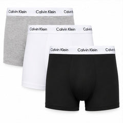 Three pairs of Calvin Klein boxer briefs arranged in a stack on a white background, showing the gray, white, and black options with the brand name printed on the waistbands.