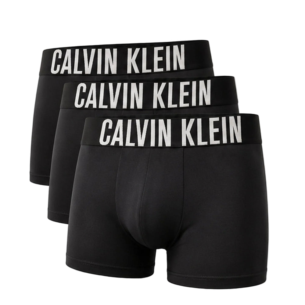 Three pairs of black Calvin Klein boxer briefs arranged in a staggered stack, each featuring a wide black waistband with 'CALVIN KLEIN' printed in bold white capital letters.