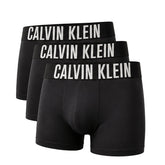 Three pairs of black Calvin Klein boxer briefs arranged in a staggered stack, each featuring a wide black waistband with 'CALVIN KLEIN' printed in bold white capital letters.