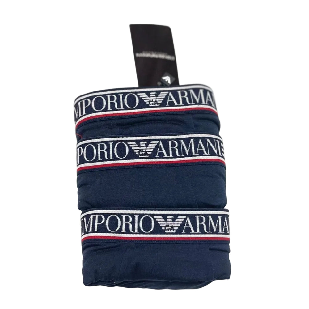 Three folded pairs of navy blue Emporio Armani boxer briefs stacked vertically, showing the signature white elastic waistband with red and blue stripes and the white brand logo.