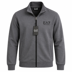 A dark gray zip-up jacket with a stand collar, featuring the 'EA7' logo on the left chest and a matching hangtag on the zipper, shown against a plain white background.