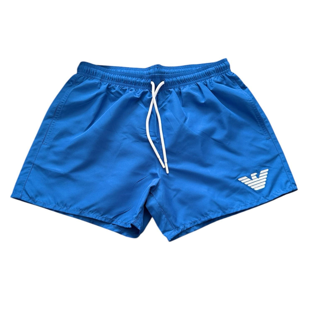 Blue athletic shorts with a white drawstring and a white embroidered eagle logo on the lower left leg, displayed against a plain white background.