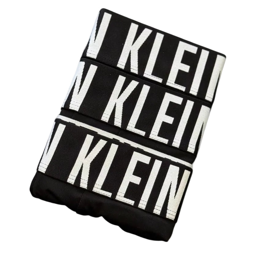 A folded black garment featuring bold white 'KLEIN' text repeated across the fabric, photographed on a plain white background.