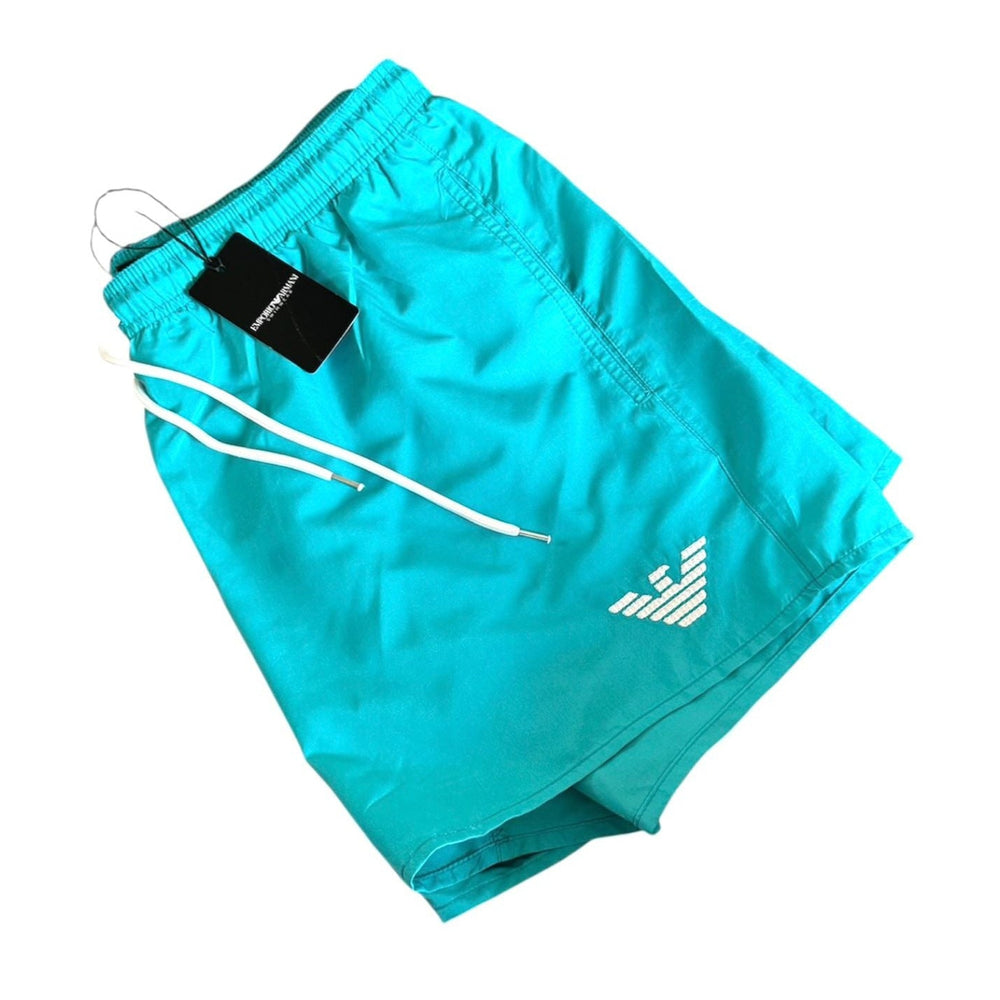 Turquoise Armani Exchange athletic shorts with a white drawstring and a white embroidered logo on the left leg, shown with a black hangtag on a white background.