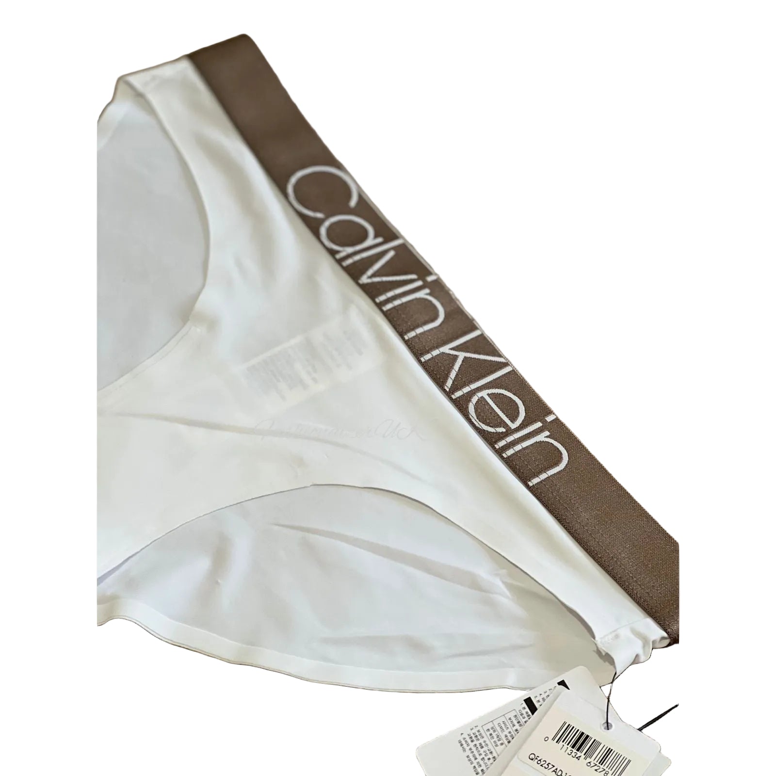 White Calvin Klein briefs laid flat on a wooden surface, showing the brown waistband with the white Calvin Klein logo and a product tag attached.