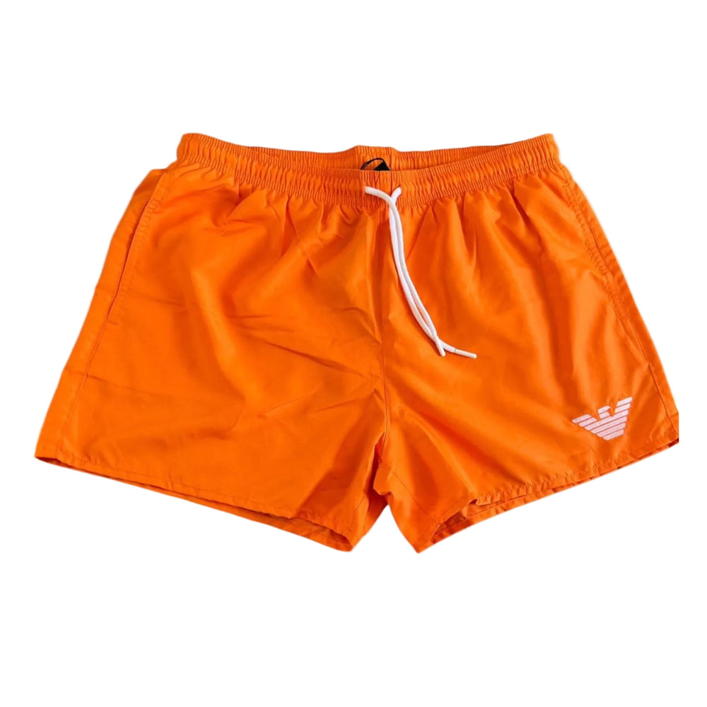Bright orange athletic shorts with a white drawstring and a white embroidered Emporio Armani eagle logo on the lower left leg, shown against a plain white background.