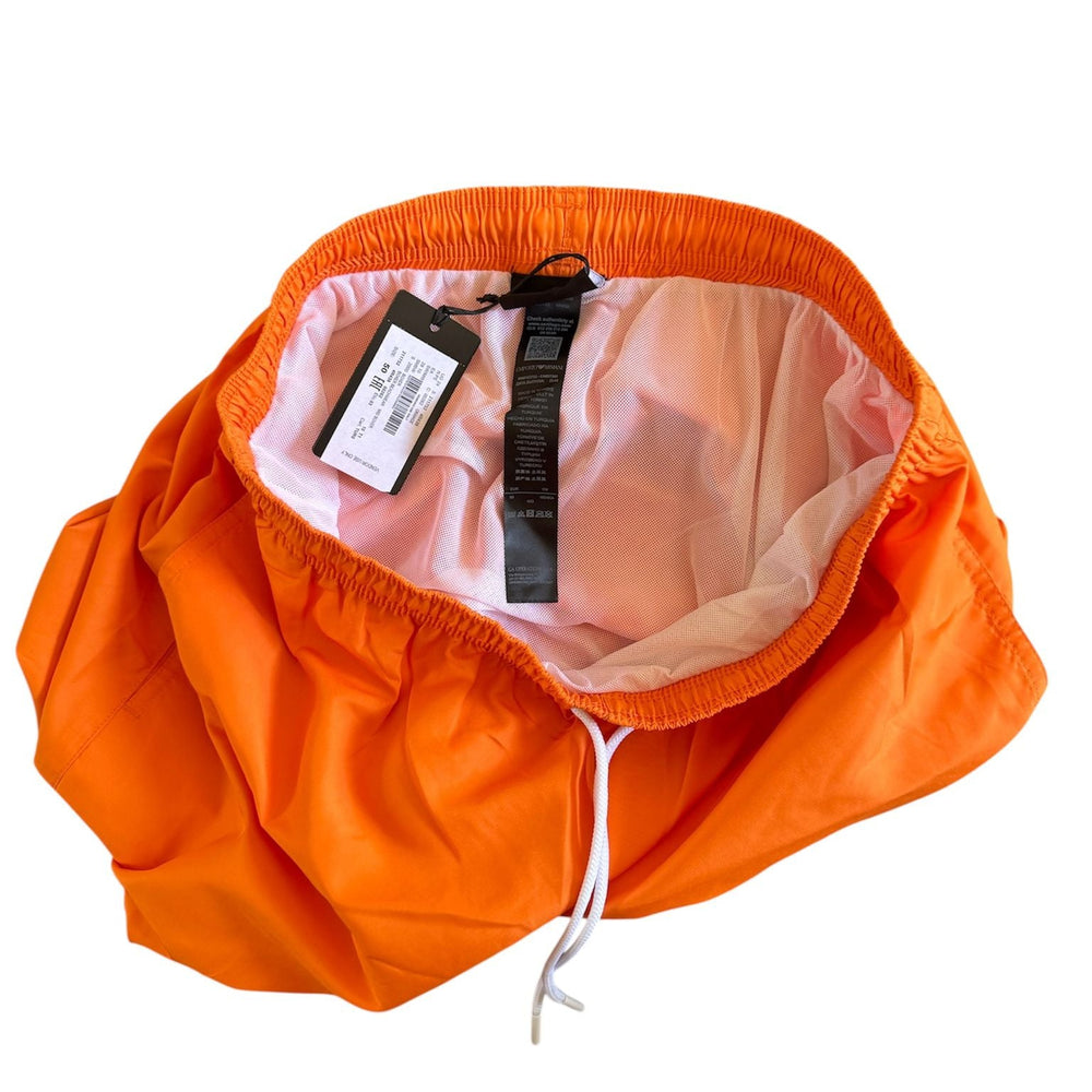 Bright orange waterproof rain jacket with a white drawstring and a light pink inner lining, shown open with a product tag attached, on a solid white background.