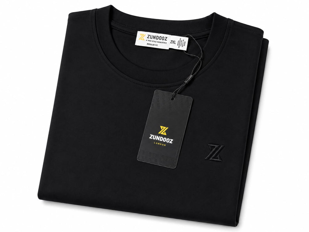 A folded black crew-neck T-shirt from ZUNDOOZ, featuring a black hangtag and a subtle black embroidered logo on the front, set against a plain white background.