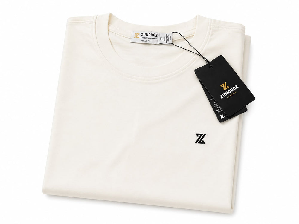 A folded off-white crewneck t-shirt with a small black 'Z' logo on the left chest, featuring a black branded hangtag and a white inner neck label. The brand name 'ZUNDOOZ' is visible on the tag.