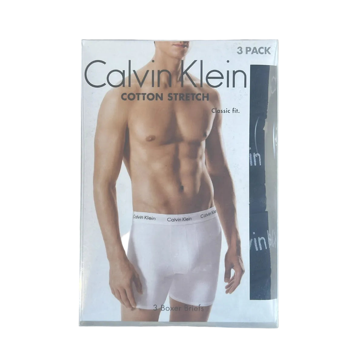 Calvin Klein 3-pack of cotton stretch boxer briefs in classic fit, shown in its original retail packaging on a light wood desk with a keyboard in the background.